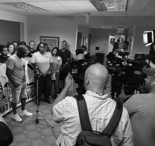 Stand Up Nashville representatives wearing branded t-shirts addressing members of the press with cameras and recorders