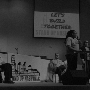 Odessa Kelly of Stand Up Nashville speaks into microphone on stage about building Nashville together