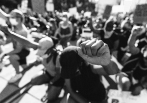 People kneeling in organized protest with heads down and fists raised in an urban Nashville