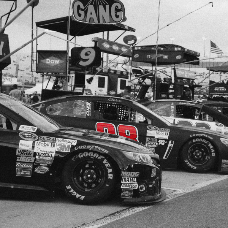 Two NASCAR cars parked in black and white with their door numbers in bright red